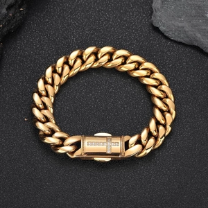 Men's gold Cuban link chain bracelet with crystal cross clasp on dark rock background