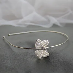 Dettaglio di un elegante cerchietto dorato con fiocco di perle e strass scintillanti