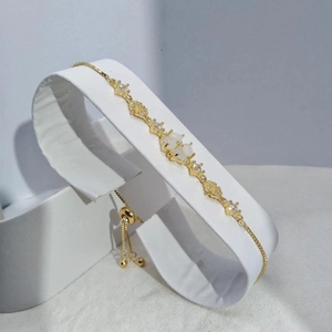 Minimalist gold clover bracelet with white cat-eye stones and cubic zirconia on stand