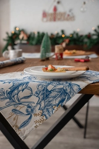 Detail of Christmas table runner with blue holly print and gold accents on linen