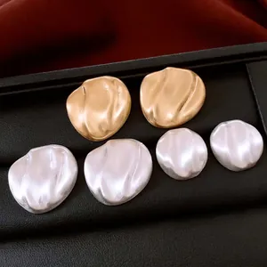 Minimalist silver and gold wavy oval stud earrings with matte brushed finish texture
