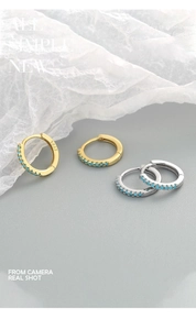 Macro view of S925 sterling silver stamp on minimalist gold and silver hoop earrings