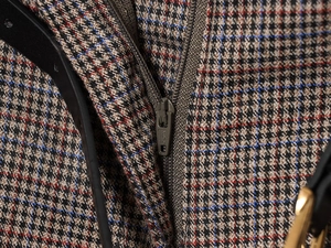 Detailed macro view of houndstooth fabric with SAB metal zipper and leather trim