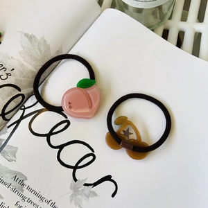 Detailed close-up of cute fruit charms on hair ties featuring peach and cherry designs