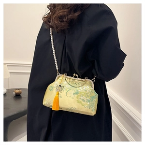 Floral embroidered kiss-lock shell bag with pearl chain and tassel on model side