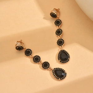 Elegante goldfarbene Tropfenohrringe mit schwarzen Kristallen und einem Tropfenstein