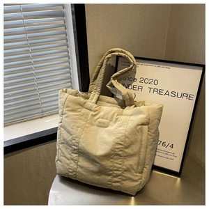 Macro shot of beige quilted nylon tote bag with high-quality stitching and texture