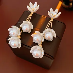 Luxurious gold floral tassel earrings with pearls and zircons on a leather background
