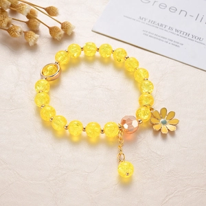 Detail of yellow crackle beaded bracelet with daisy charm on a beige texture background