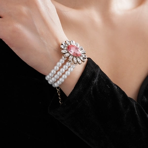 Gros plan d'un bracelet de perles multicouche avec pierre rose et fleur de strass