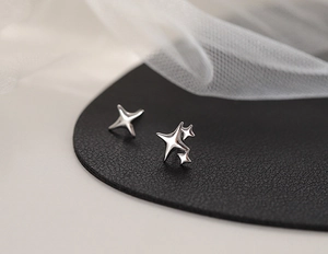 Macro detail of asymmetric silver star stud earrings on elegant textured background