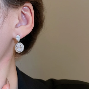 Macro view of a silver oval rhinestone double-drop earring worn by a model