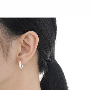 Detailed macro view of S925 sterling silver hoop earrings with wrinkled texture on model