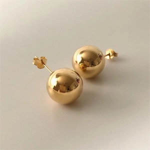 Detail view of a polished gold spherical stud earring with secure butterfly clasp closure