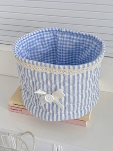 Detailed view of blue striped lace storage basket with bow detail on decorative books