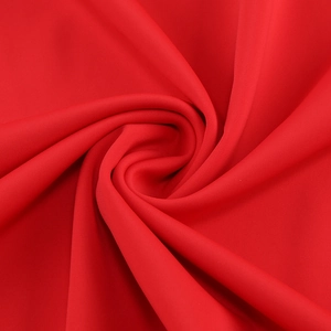 Detailed close-up of red knitted fabric texture with spiral rose petal-like folds