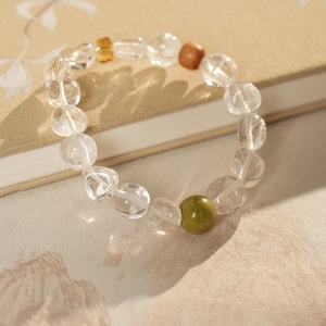Détail des perles en cristal blanc et jade vert sur un bracelet en bois de santal
