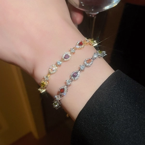 Close-up of elegant gold and silver bracelets with teardrop-shaped colorful zircons