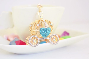 Détail du porte-clés carrosse citrouille doré avec motif de cœur en strass bleus brillants