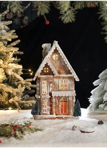 Detailed view of the illuminated wooden Christmas cottage with snowy roof and warm LED lights