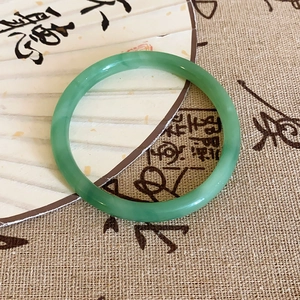 Vue détaillée d'un bracelet en jade vert clair sur un éventail oriental et calligraphie d'art