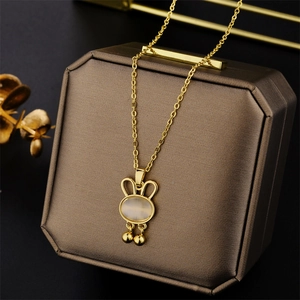 Golden cat eye opal rabbit pendant necklace with bells on a brown jewelry box