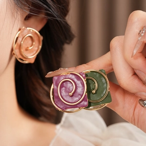 Close-up of vintage square spiral earrings with colorful enamel finish on gold metal