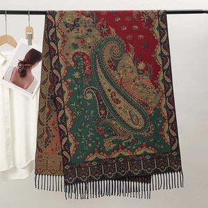 Detail of red and green paisley jacquard scarf with decorative fringe on a metal rack