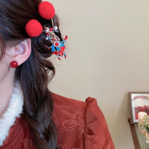 Detail of red pompom hair clips and butterfly hairpin worn on model's hair