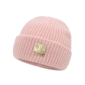 Close-up of pink knit baby beanie featuring a golden smiley face leather patch detail