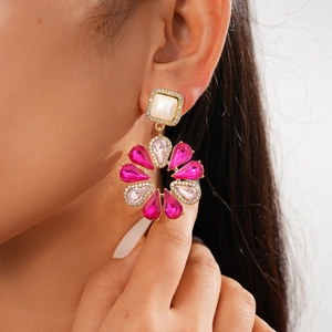 Close-up of pink crystal flower earrings with gold accents on a fashion model