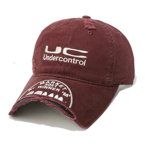 Detail of distressed burgundy baseball cap featuring white embroidery and shark tooth brim