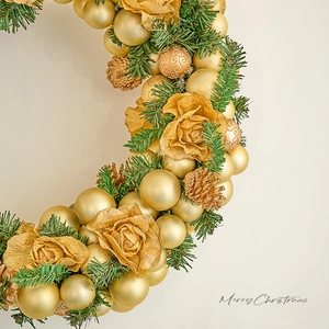 Golden Christmas wreath with pine needles, ornaments and Merry Christmas sign on white background