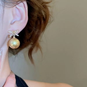 Close-up of model wearing zircon bow earrings with a champagne pearl drop pendant