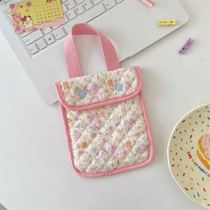 Detailed view of pink quilted handbag with floral patterns and light blue snap buttons