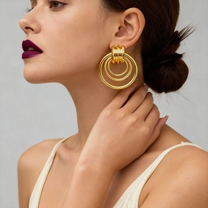 Detail shot of a model wearing hollow geometric gold multi-loop earrings with a glossy finish