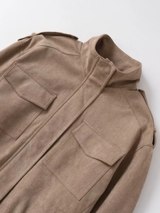 Detailaufnahme einer braunen Wildlederjacke mit Schulterklappen und einer Pattentasche