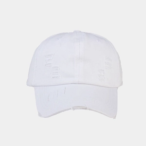 Detailed close-up of white distressed baseball cap with vintage frayed edges and torn cotton fabric