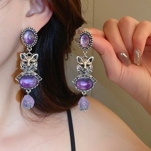 Detailed close-up of vintage cat-shaped drop earrings with purple stones and silver finish