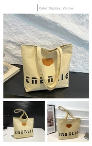 Close-up of a large yellow canvas tote bag with brown leather patch and black lettering