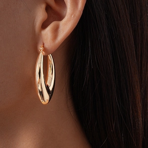 Close-up of a gold hollow waterdrop twisted hoop earring with a glossy metallic finish
