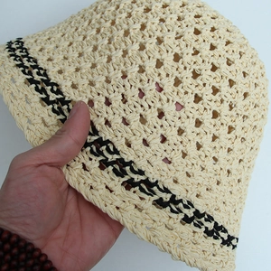 Detail of hand-crocheted straw hat texture with black stripe accents on beige brim