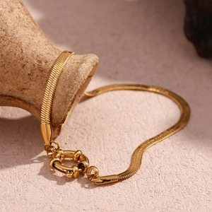Artistic display of 18K gold plated snake chain bracelet wrapped on a vintage ceramic jar