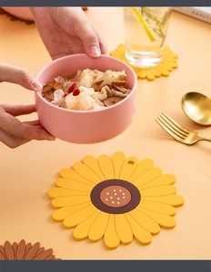 Close-up of a sunflower silicone heat resistant mat with a bowl and golden cutlery