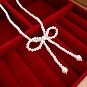 Close-up of pearl woven bow necklace on luxury red velvet background for women