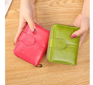 Close-up of pink and green short leather wallets with zipper and stitching details