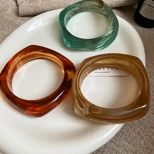 Three-piece irregular acrylic resin bangles in teal, amber, and cream colors