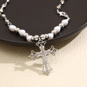 Close-up of a silver cross pendant with crystals on an irregular faux pearl necklace