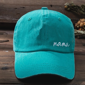 Detail of teal washed cotton baseball cap featuring white mama embroidery and stitching