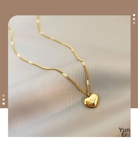 Detail of gold heart pendant with Love engraving on a textured intertwined chain link